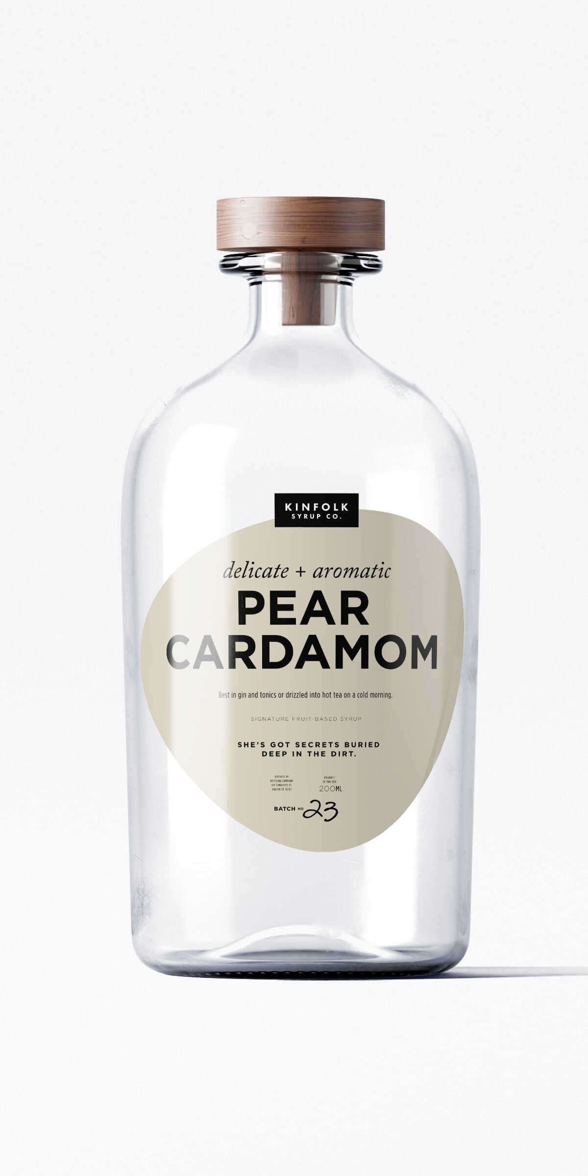 The Pear Cardamom bottle: same apothecary glass and wooden cap, bone-cream teardrop label.