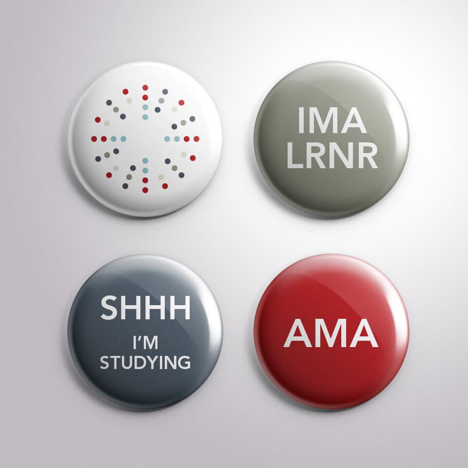 Four pins arranged in a square: top-left, the Signet mark on white; top-right, an olive pin reading IMA LRNR; bottom-left, a slate pin reading SHHH I'M STUDYING; bottom-right, a red pin reading AMA.