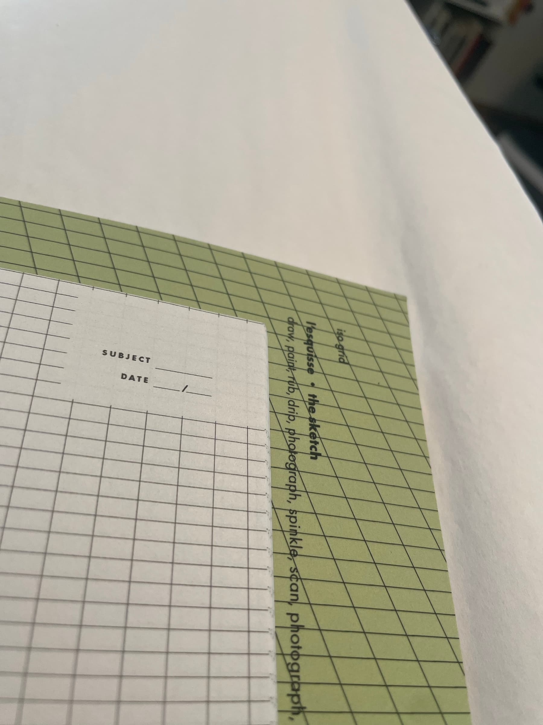 An interior page of the Grid book: a lavender ground with a fine-grained square grid printed underneath, PROCESS AND EXPERIENCE set in stacked black caps reading vertically up the right edge. A yellow and pale-green page peeks from the layered stack underneath.