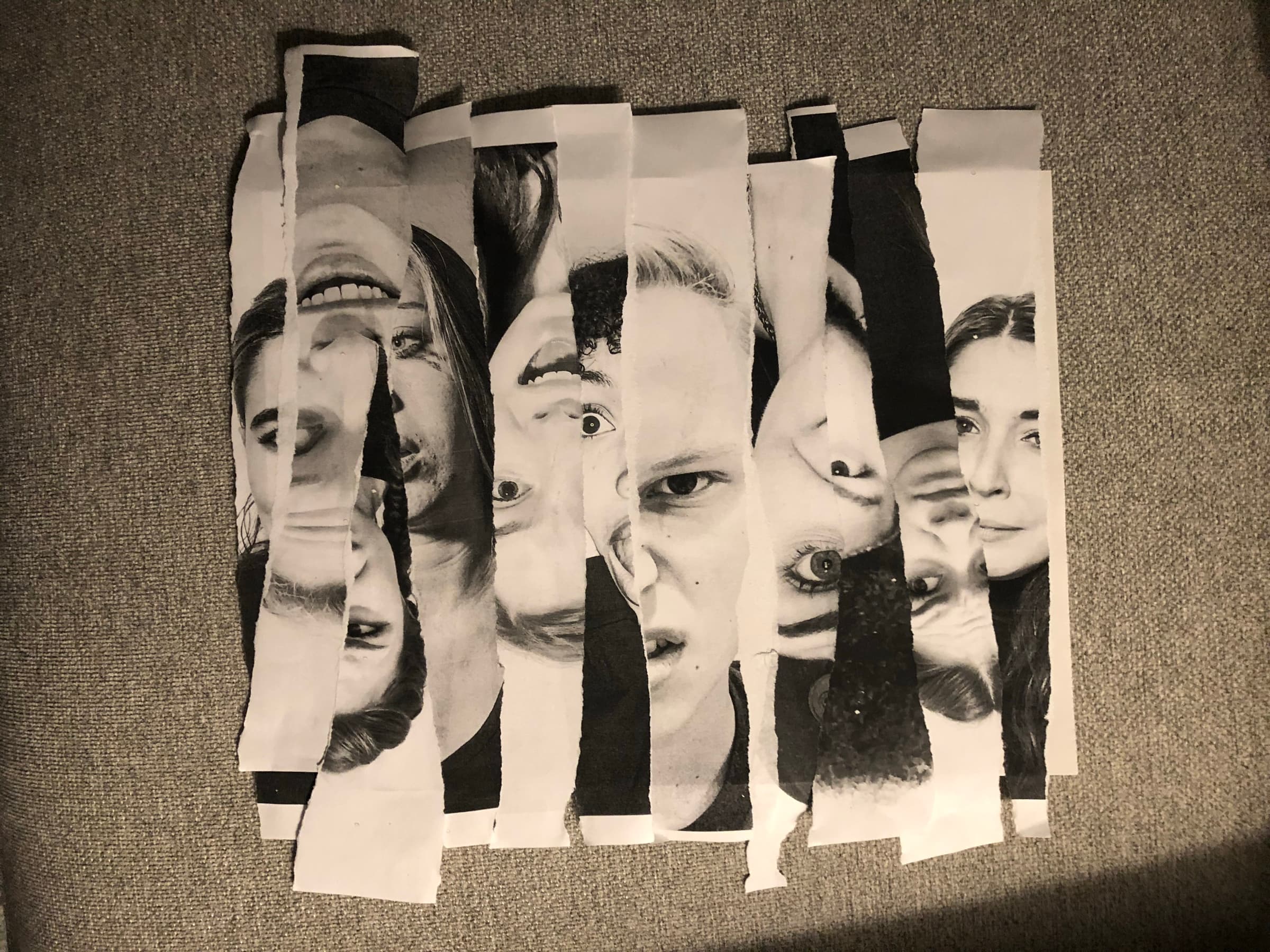 The torn-paper Cyberstock composition in progress: black-and-white face fragments cut into vertical strips, taped onto a grey woven background, the actors' eyes and mouths broken across the strips.